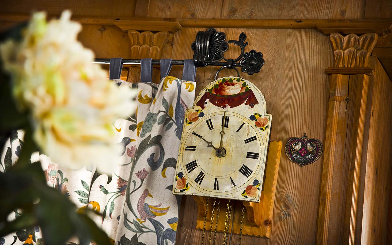 Detail einer alten Uhr mit Blumen an einer Holzwand