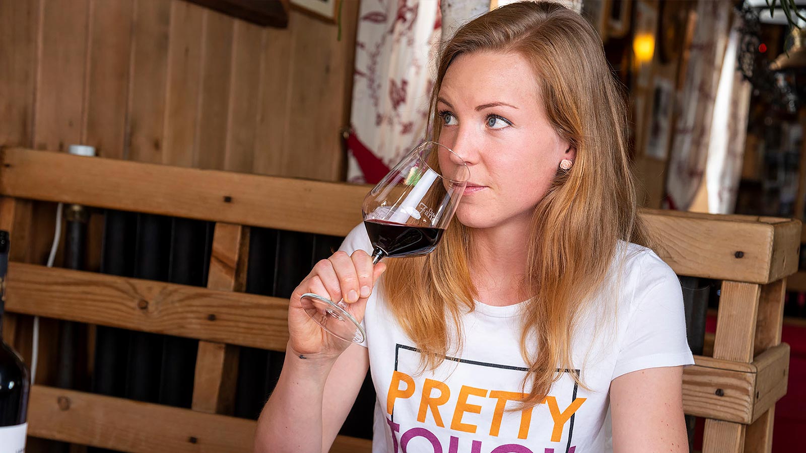 Eine junge Frau, die ein Glas Rotwein in der Fanes Hütte trinkt