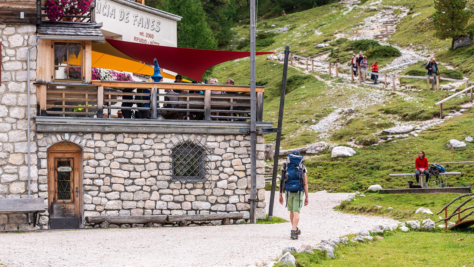 Dettaglio di una parte del Rifugio Fanes e sullo sfondo un gruppo di persone di ritorno da un'escursione